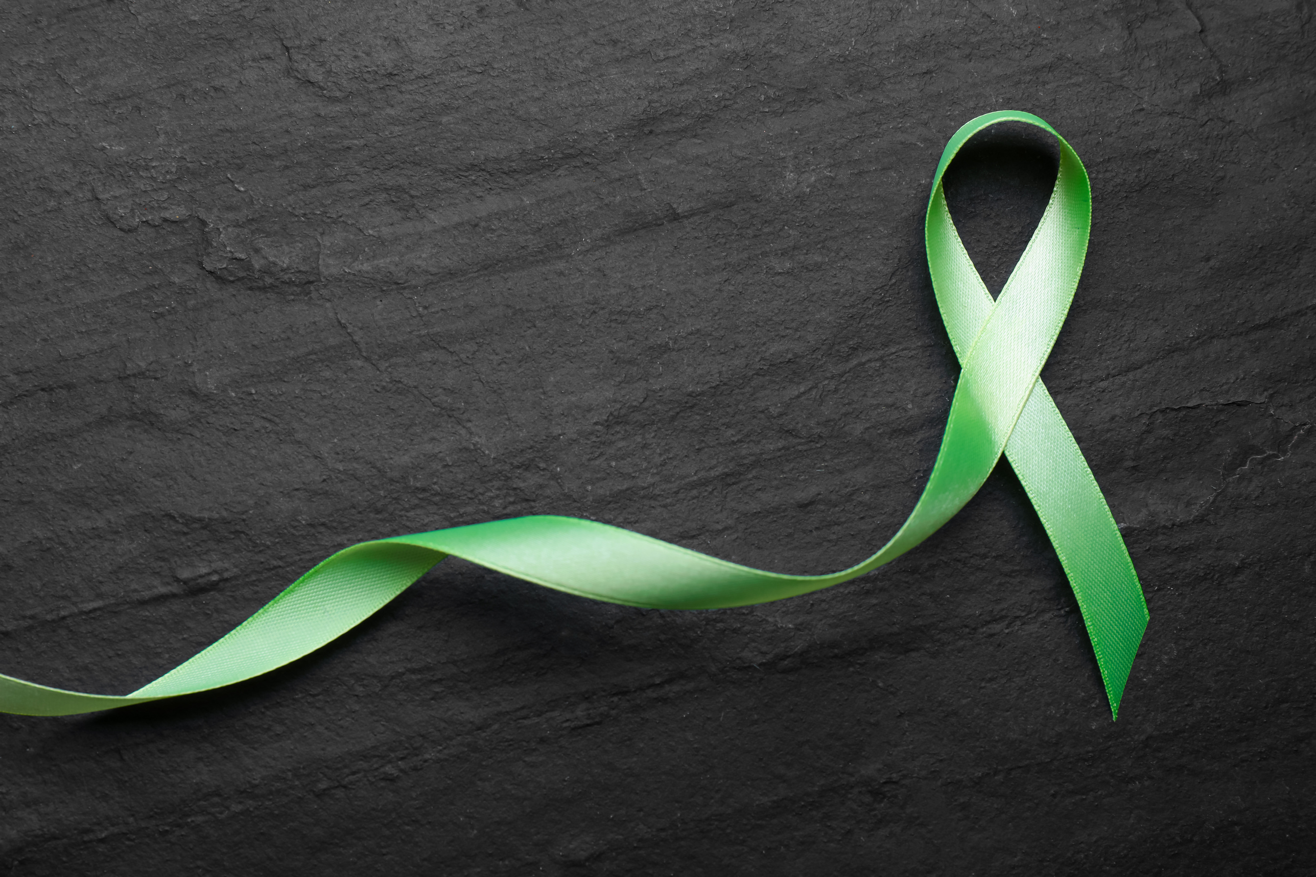 World Mental Health Day. Green Ribbon on Black Background, Top V